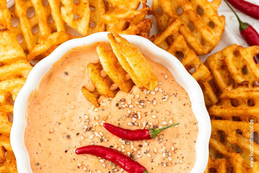 Sriracha Mayonnaise in einer Schale, dekoriert mit Chilis und Sesam