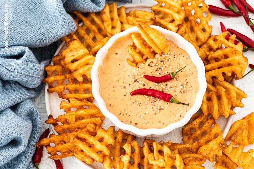 Sriracha Mayonnaise in einer Schale, dekoriert mit Chilis und Sesam