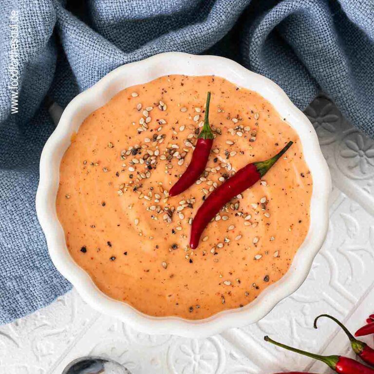 Sriracha Mayonnaise in einer Schale, dekoriert mit Chilis und Sesam