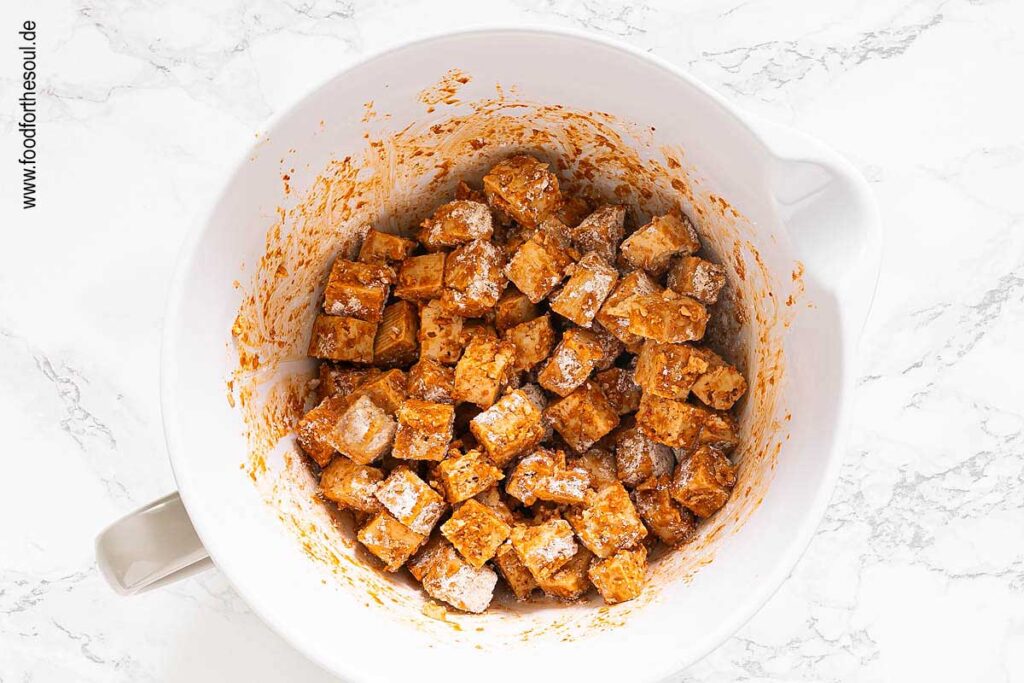 Speisestärke und Hefeflocken über marinierten Tofu geben und mischen - Schritt 3