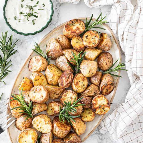 Im Airfryer frittierte Rosmarinkartoffeln angerichtet mit auf einer Servierplatte