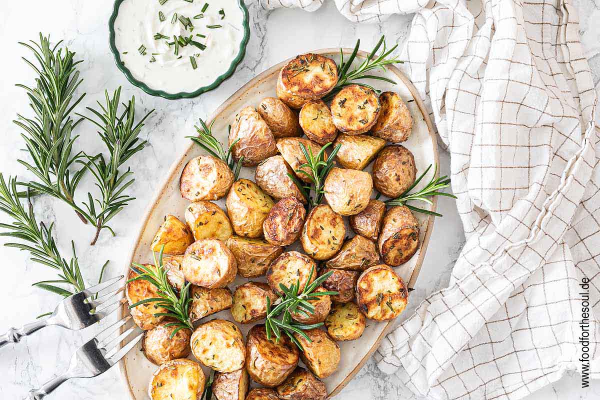 Im Airfryer frittierte Rosmarinkartoffeln angerichtet mit auf einer Servierplatte