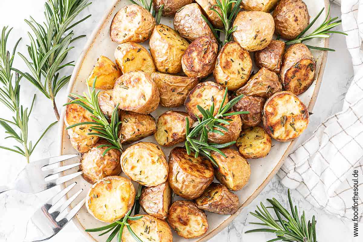 Im Airfryer frittierte Rosmarinkartoffeln angerichtet mit auf einer Servierplatte