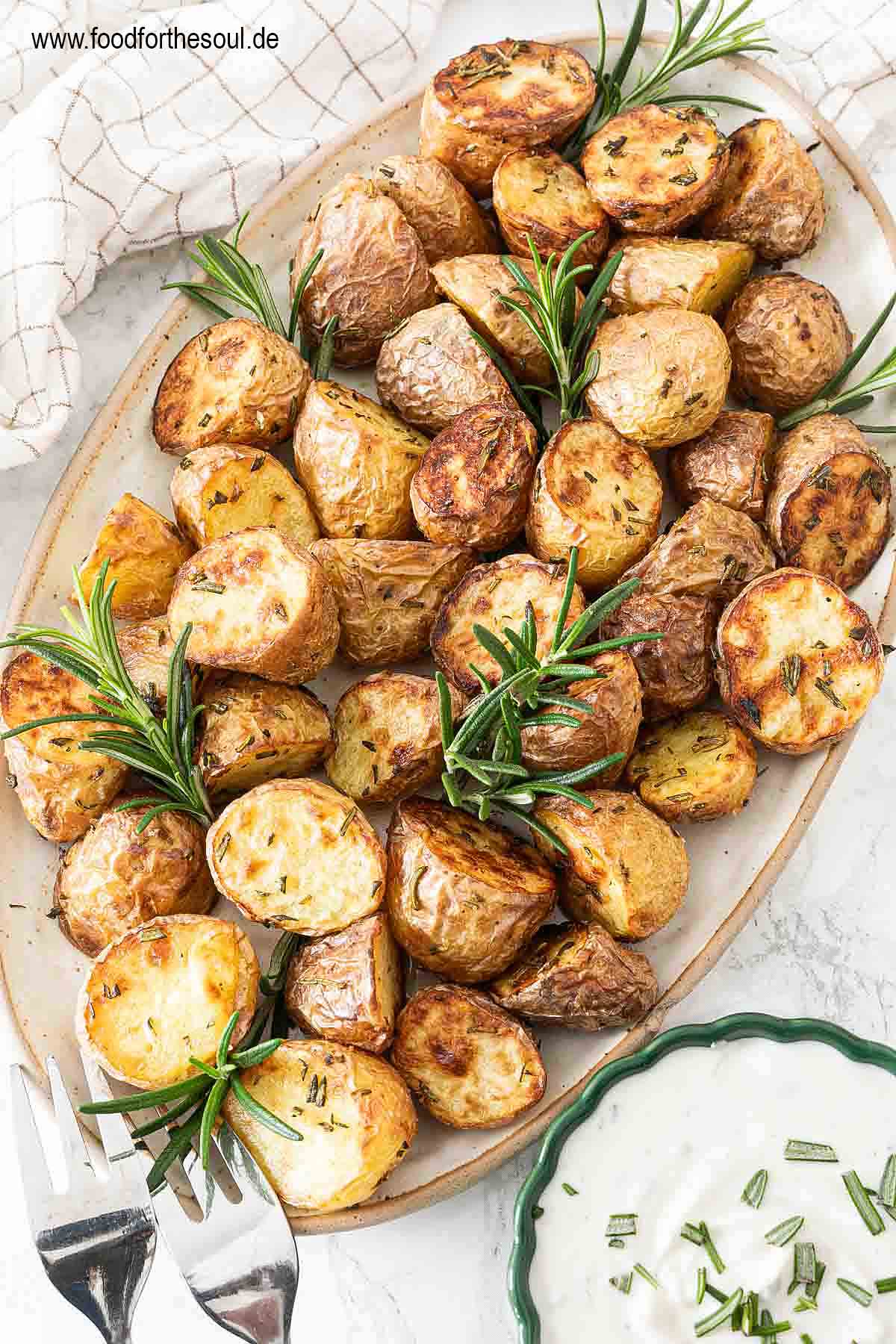 Im Airfryer frittierte Rosmarinkartoffeln angerichtet mit auf einer Servierplatte