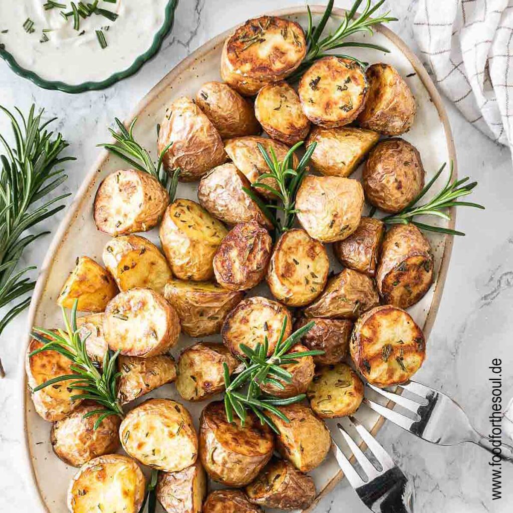 Im Airfryer frittierte Rosmarinkartoffeln angerichtet mit auf einer Servierplatte