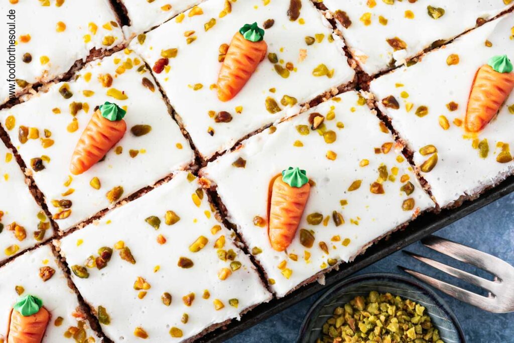 Karottenkuchen dekoriert mit Marzipan-Möhren und gehackten Pistazien