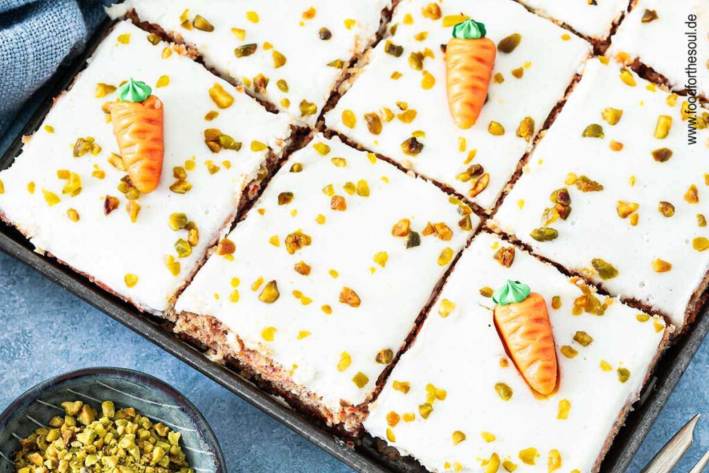 Karottenkuchen dekoriert mit Marzipan-Möhren und gehackten Pistazien