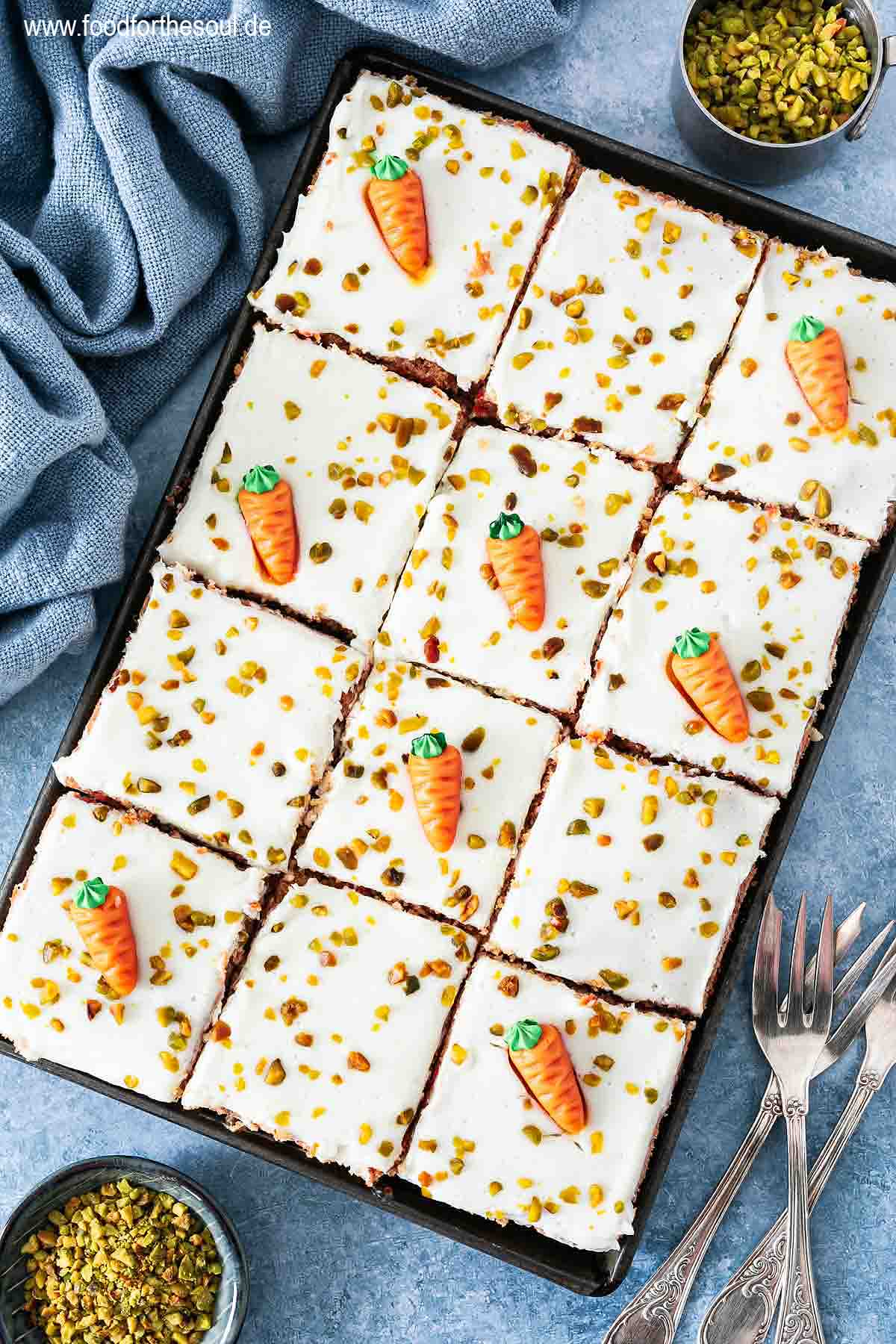 Karottenkuchen dekoriert mit Marzipan-Möhren und gehackten Pistazien