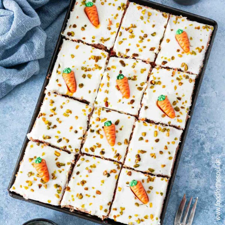 Karottenkuchen dekoriert mit Marzipan-Möhren und gehackten Pistazien