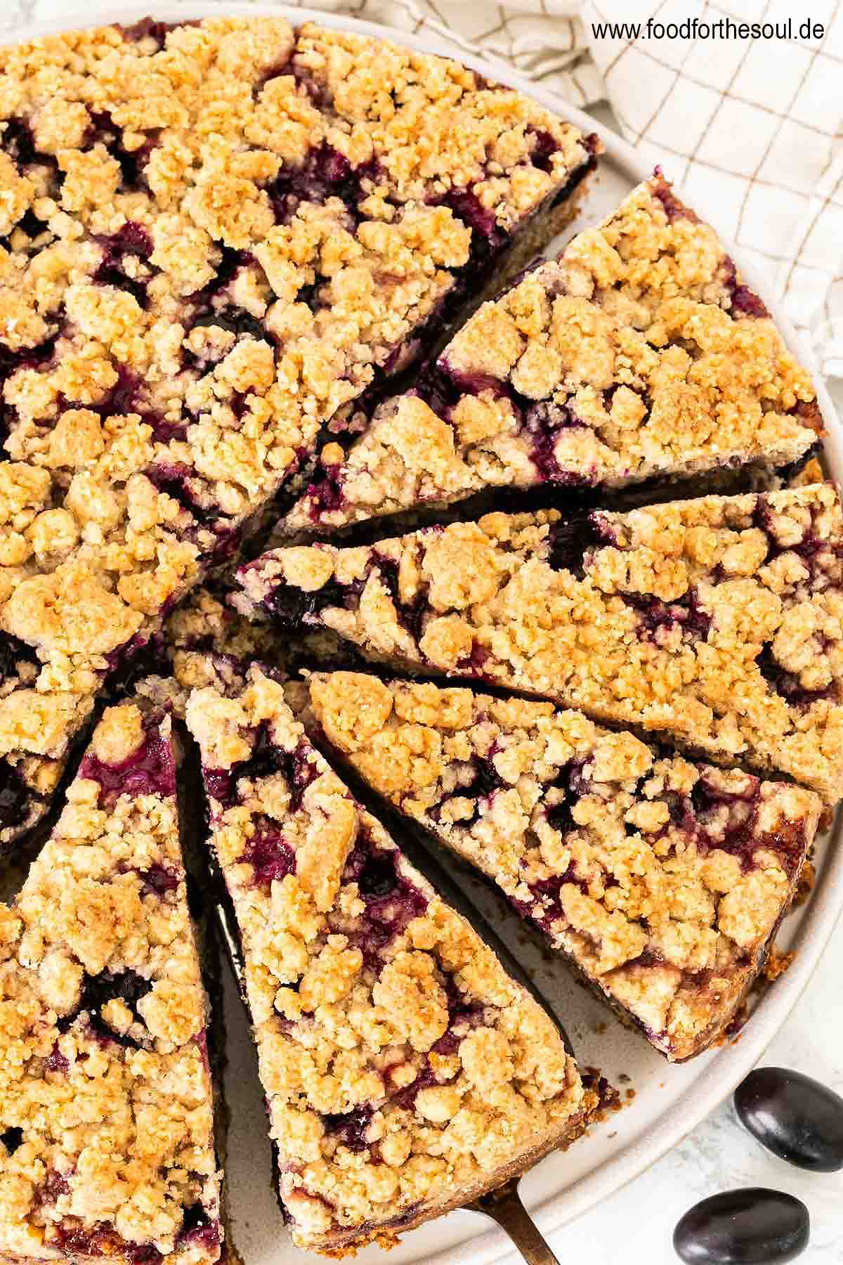 Traubenkuchen mit Streusel auf einem Teller mit Tortenheber