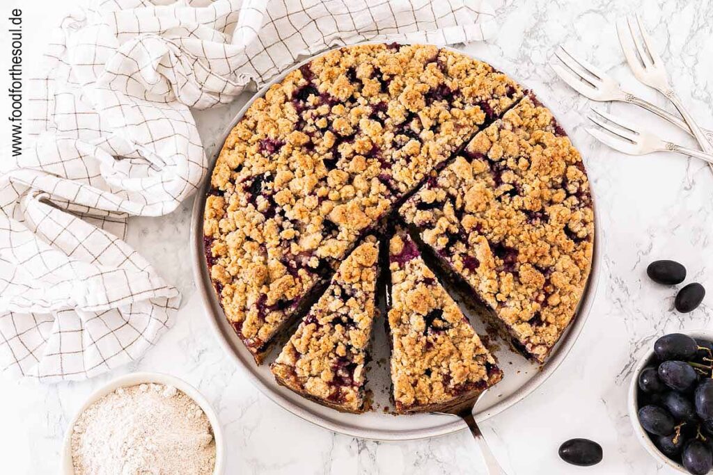 Traubenkuchen mit Streusel auf einem Teller mit Tortenheber