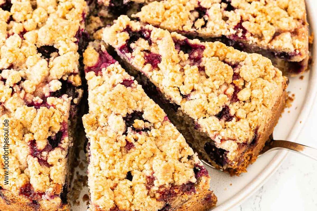 Traubenkuchen mit Streusel auf einem Teller mit Tortenheber