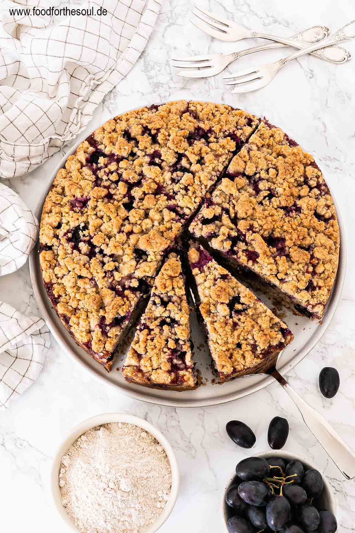 Traubenkuchen mit Streusel auf einem Teller mit Tortenheber