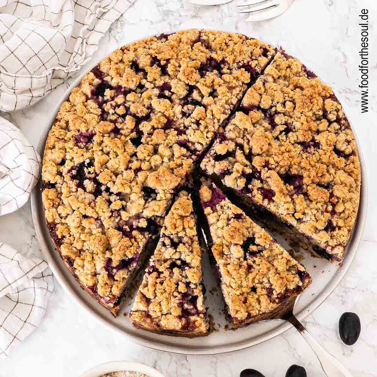 Traubenkuchen mit Streusel auf einem Teller mit Tortenheber