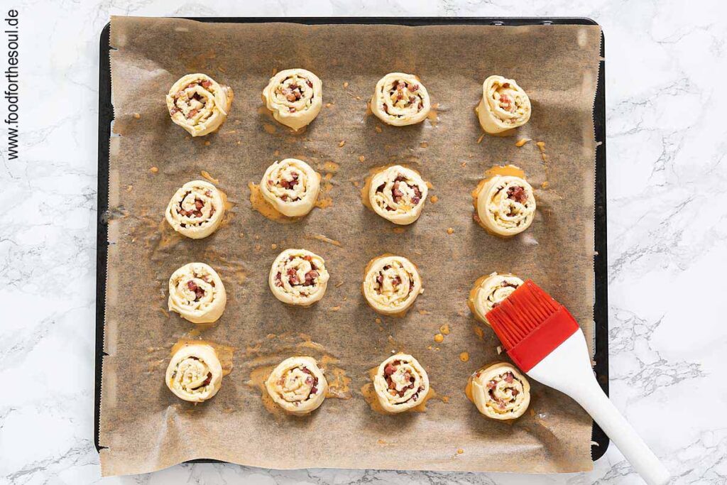 Blätterteigschnecken auf ein Backblech setzen und mit verquirltem Ei bepinseln - Schritt 8