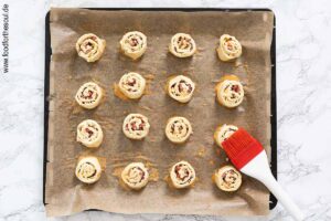 Blätterteigschnecken auf ein Backblech setzen und mit verquirltem Ei bepinseln - Schritt 8