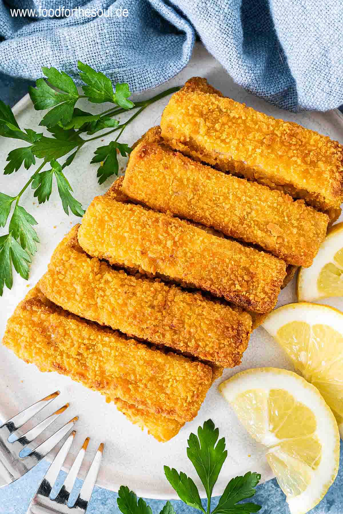 Knusprige Airfryer Fischstäbchen angerichtet mit Zitronenscheiben auf einem Teller