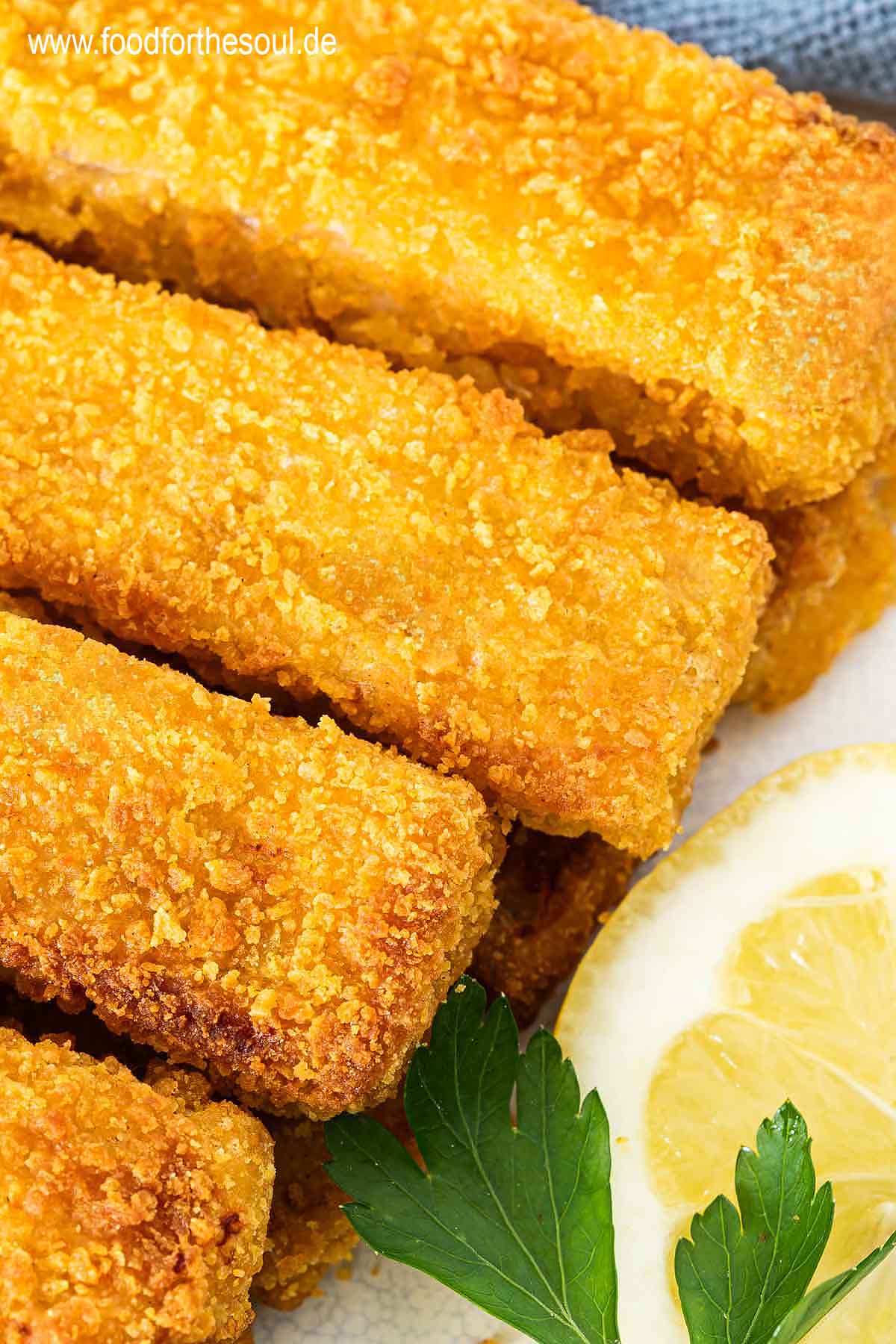 Knusprige Airfryer Fischstäbchen angerichtet mit Zitronenscheiben auf einem Teller