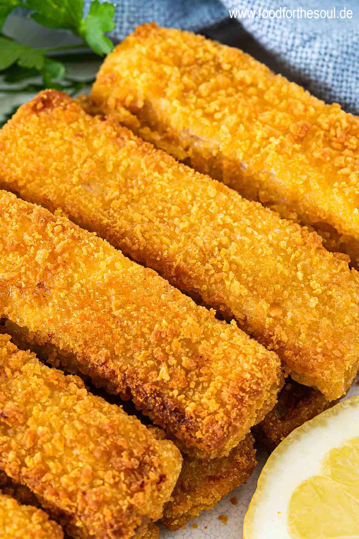 Knusprige Airfryer Fischstäbchen angerichtet mit Zitronenscheiben auf einem Teller
