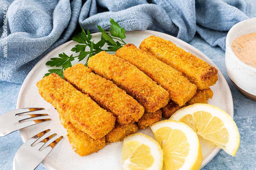 Knusprige Airfryer Fischstäbchen angerichtet mit Zitronenscheiben auf einem Teller
