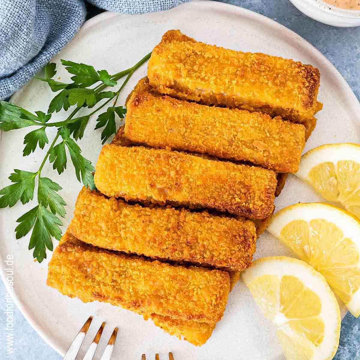 Knusprige Airfryer Fischstäbchen angerichtet mit Zitronenscheiben auf einem Teller