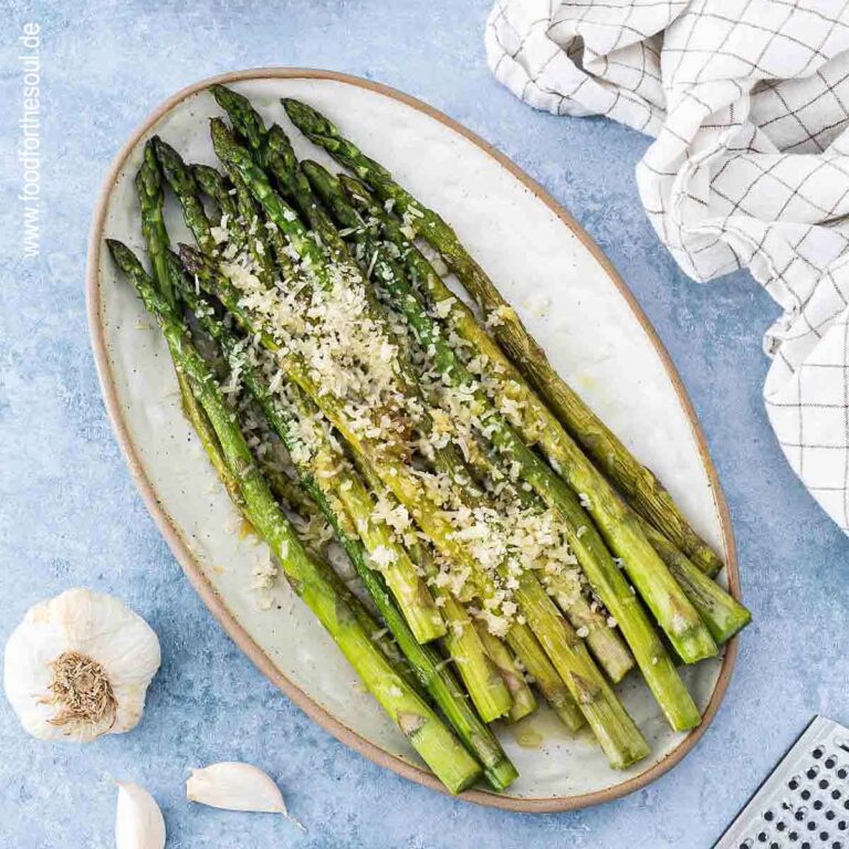 Grüner Spargel angerichtet mit Parmesan und Knoblauch auf einer Servierplatte