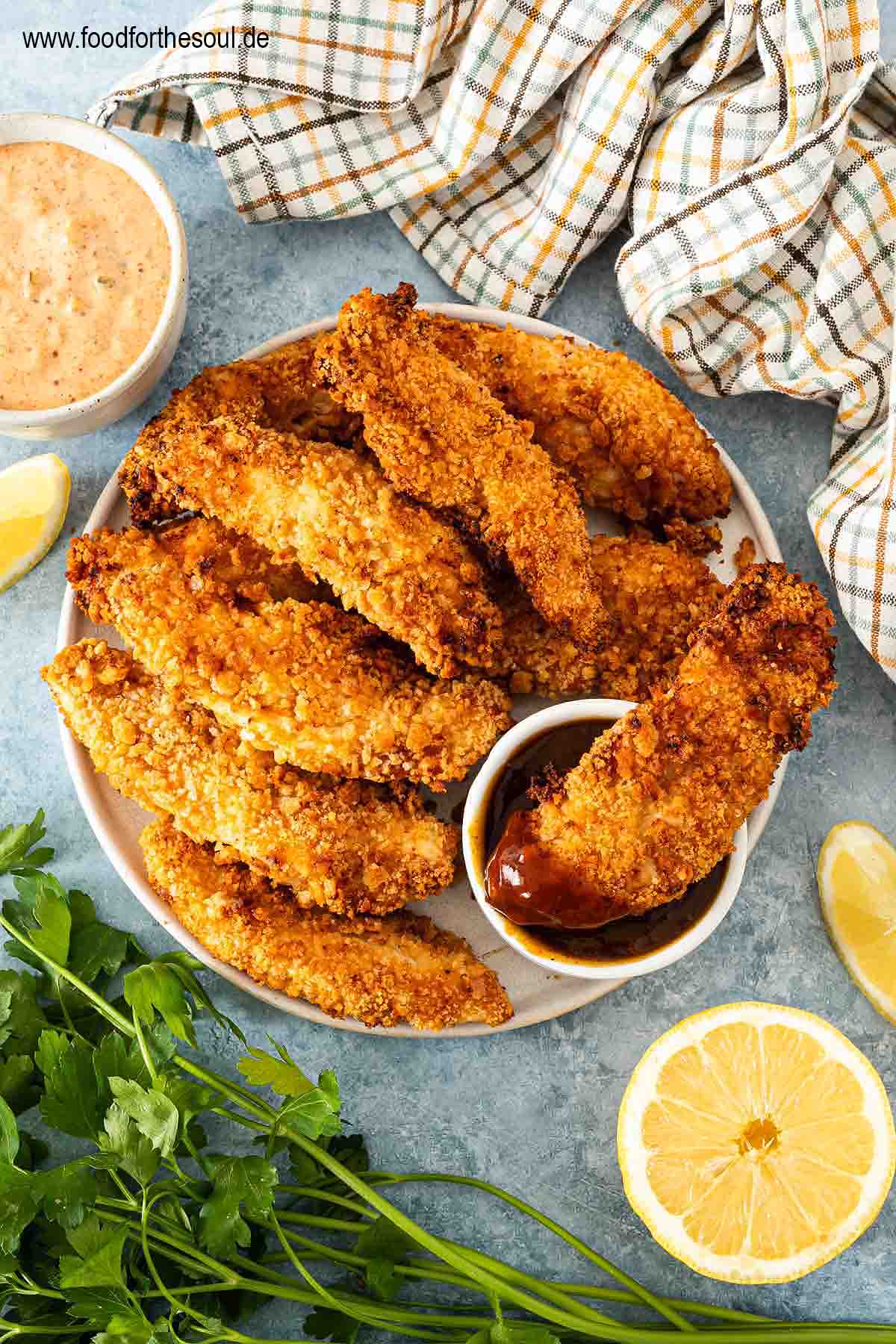 Panierte Hähncheninnenfilets angerichtet auf einem Teller mit BBQ Sauce