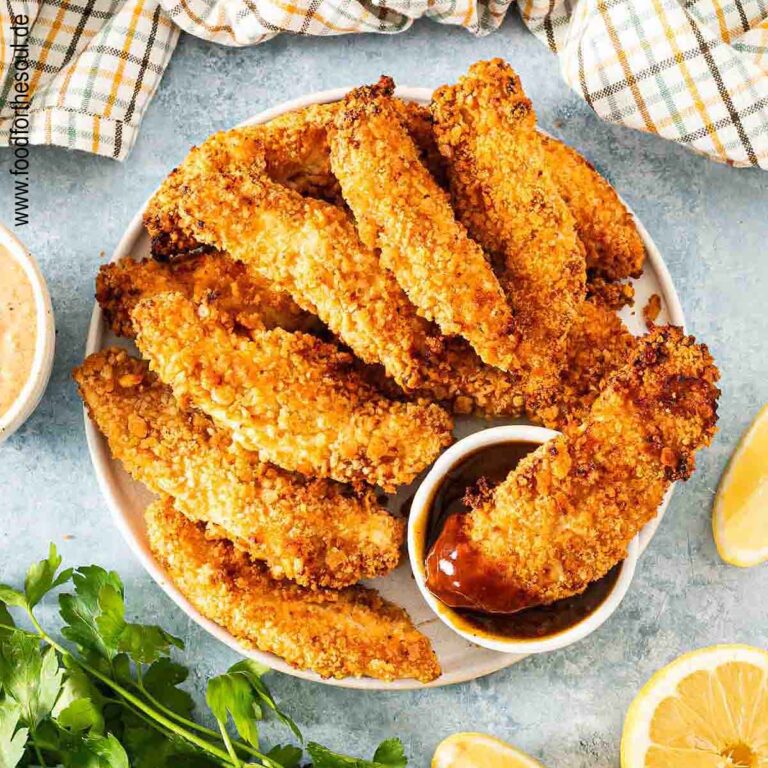 Panierte Hähncheninnenfilets angerichtet auf einem Teller mit BBQ Sauce