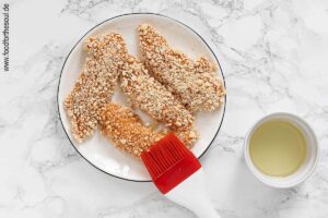 Panierte Hähncheninnenfilets mit Pflanzenöl einpinseln - Schritt 4