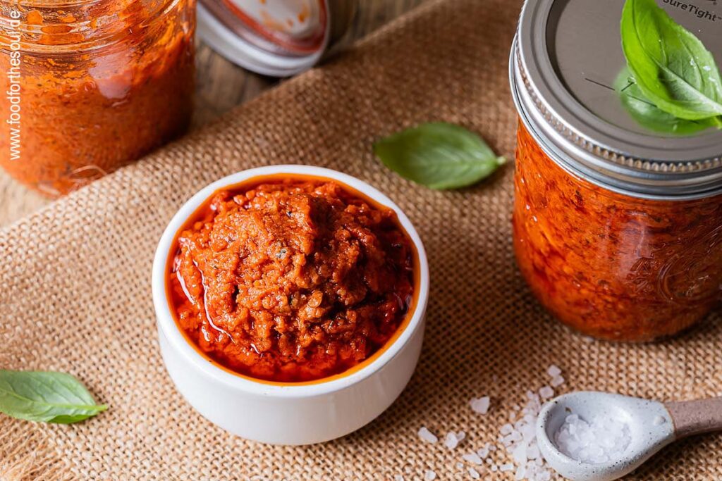 Selbstgemachtes Tomatenpesto in einer Schale und Gläsern