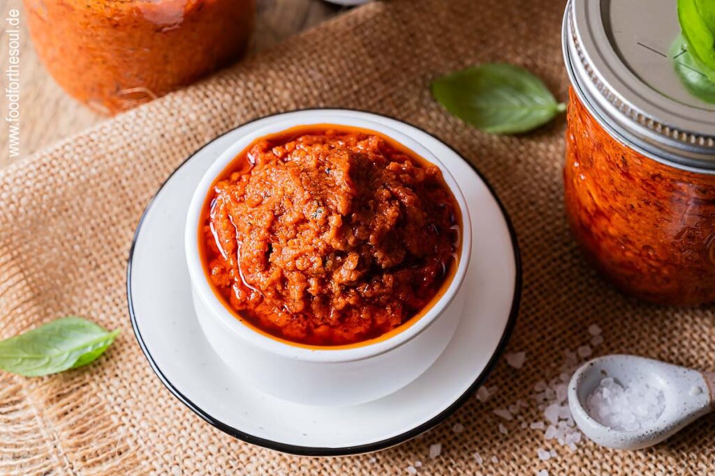 Selbstgemachtes Tomatenpesto in einer Schale und Gläsern
