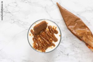 Vor dem Servieren Lotus Biscoff Dessert mit Kekskrümeln, halbem Keks und optional Lotus Creme garnieren - Schritt 4