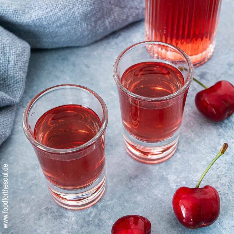 Selbstgemachter Kirschlikör in einer Flasche und zwei Schnapsgläsern