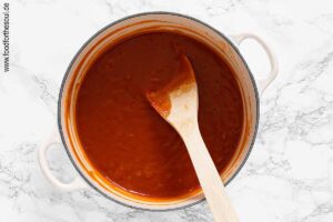 Ketchup sowie Salz, Pfeffer und Zucker hinzufügen und Soße aufkochen lassen - Schritt 5