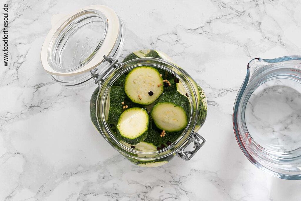 Zucchini und Zwiebel im Glas schichten, Gewürze hinzufügen und mit Essigsud auffüllen - Schritt 4