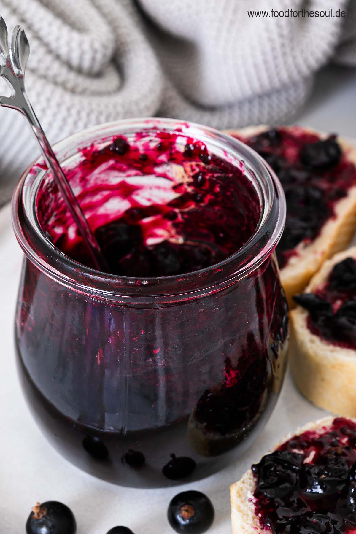 Selbstgemachte Johannisbeermarmelade in einem Glas und auf Baguettescheiben