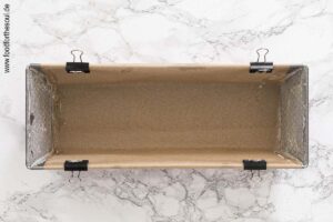 Kastenform mit Backpapier auskleiden und die Seiten einfetten und bemehlen