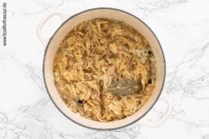 Mit Gemüsebrühe ablöschen und Sauerkraut sowie Gewürze hinzufügen - Schritt 3