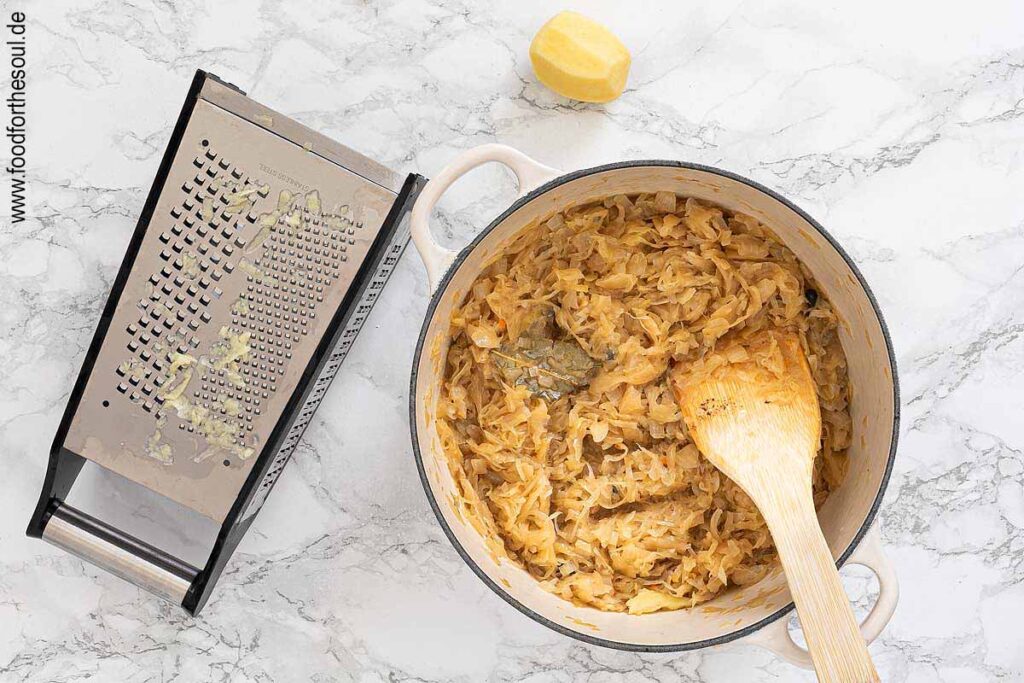 Eine kleine Kartoffel reiben und unter das Sauerkraut rühren - Schritt 4