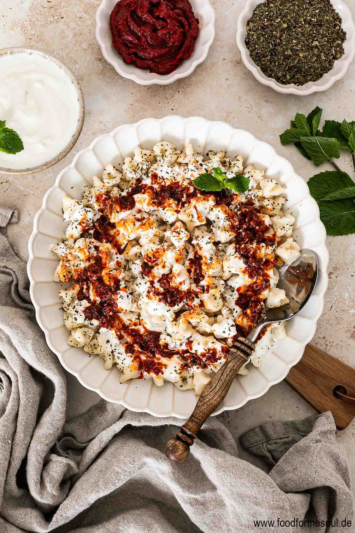 Frisch gekochte türkische Manti mit Joghurtsauce und Tomaten-Paprikabutter auf einem Teller