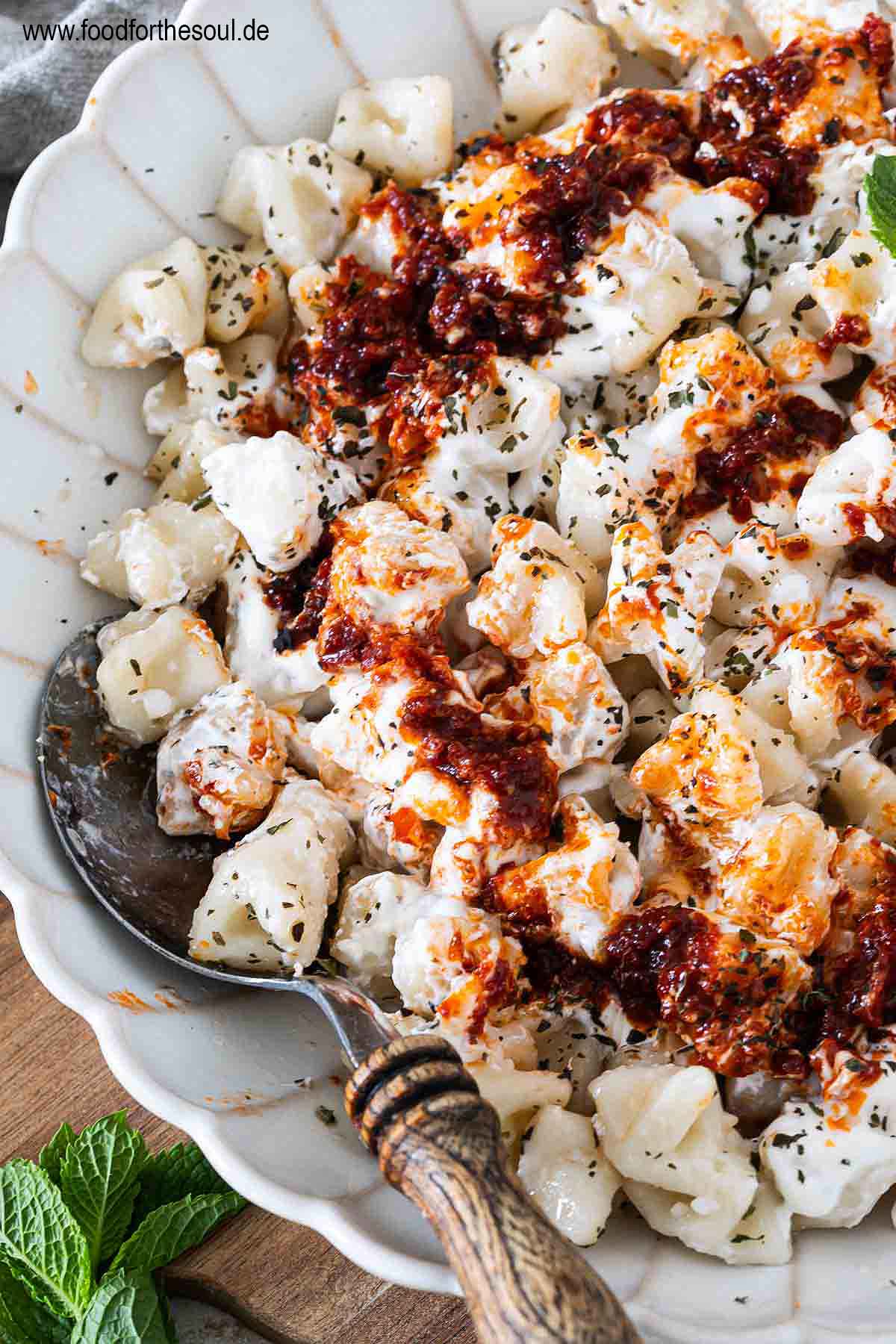 Frisch gekochte türkische Manti mit Joghurtsauce und Tomaten-Paprikabutter auf einem Teller