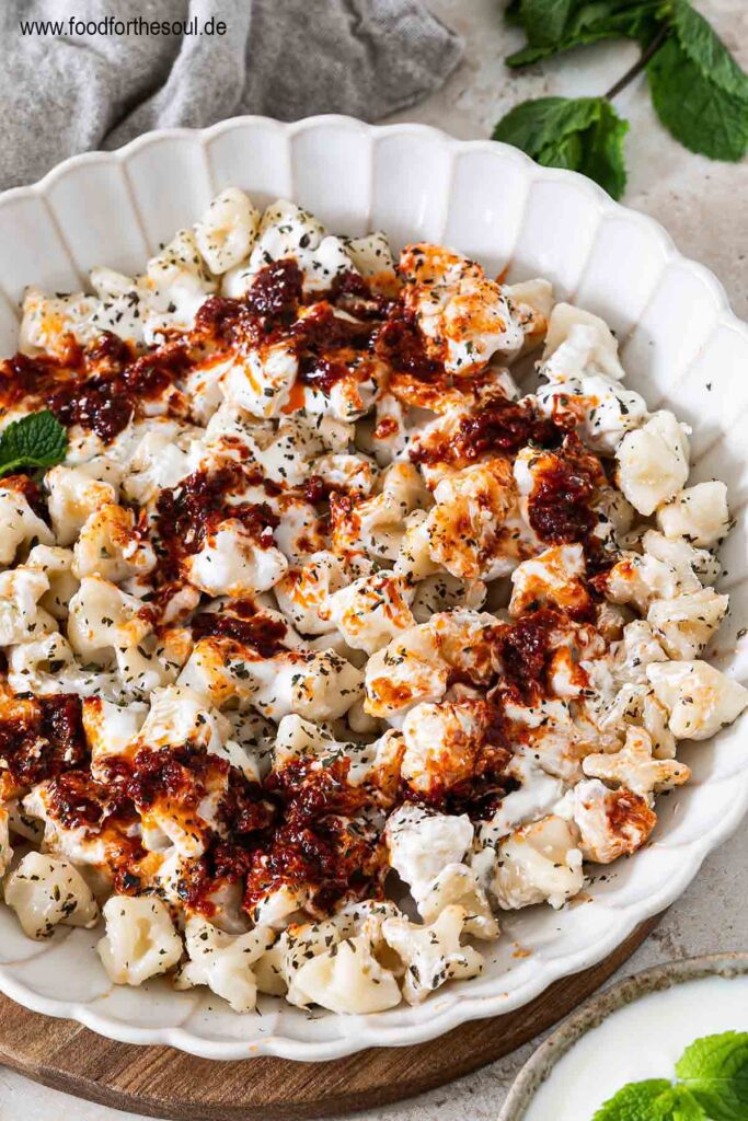 Frisch gekochte türkische Manti mit Joghurtsauce und Tomaten-Paprikabutter auf einem Teller