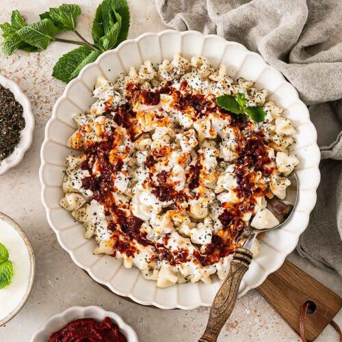 Frisch gekochte türkische Manti mit Joghurtsauce und Tomaten-Paprikabutter auf einem Teller