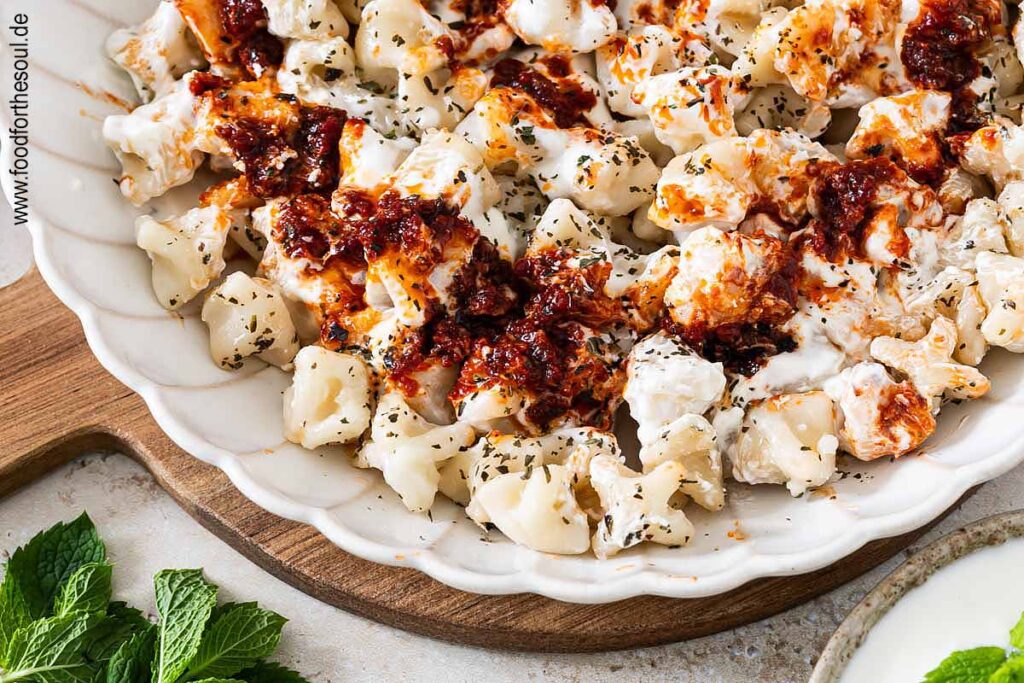 Frisch gekochte türkische Manti mit Joghurtsauce und Tomaten-Paprikabutter auf einem Teller