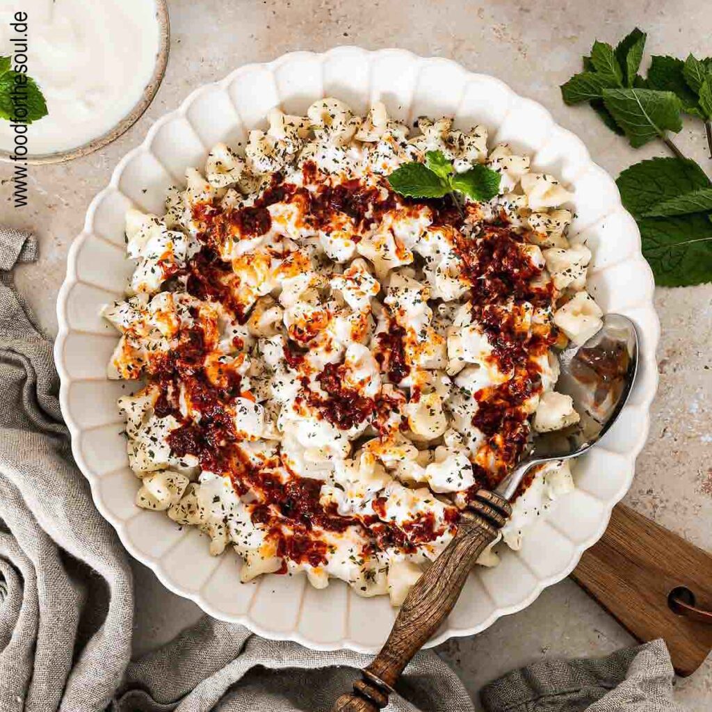 Frisch gekochte türkische Manti mit Joghurtsauce und Tomaten-Paprikabutter auf einem Teller